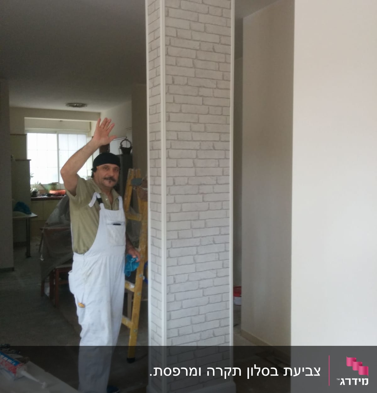 אדם עם סרבל צובע עמוד עם טפט לבנים